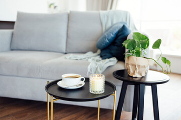 Large white cup of coffee and lit scented candle on round black coffee table