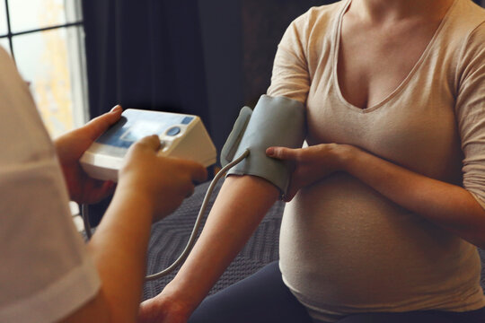 Hypertension in pregnancy. Doctor measuring blood pressure of pregnant woman