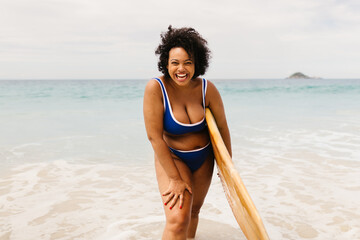 Excited surfer having fun on a beach vacation, wearing a bikini and holding a surfboard