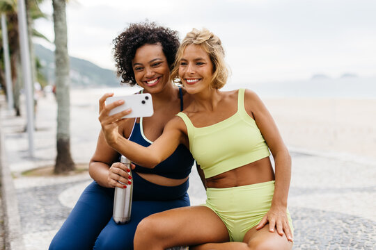 Beach workout vibes: Fit women taking a selfie on the beach promenade