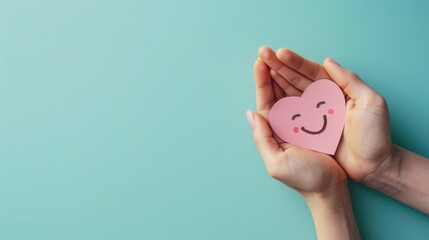 Fototapeta na wymiar Hand Holding a Pink Paper Smile Symbolizing Emotional Mental Health and Love on a Blue Background, Top-down view, Heart-Shaped Smiley, Support Positivity, Wellness, and Happiness Concept