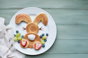 Fun, creative pancake bunny rabbit with fluffy tail hopping away for children with whipped cream...