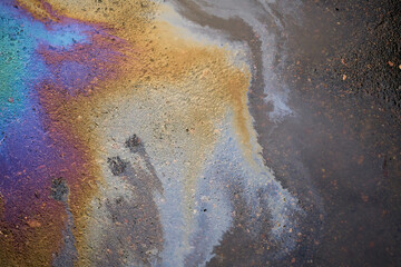 Fototapeta na wymiar Rain washed away car oil or fuel flowing from a faulty car in a parking lot.