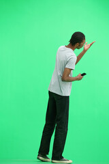 A man in a gray T-shirt, on a green background, full-length, with a phone