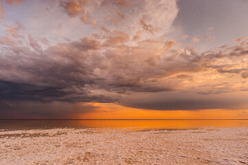Sunset or sunrise sky. Clouds over water. Golden Dawn. Dramatic coast nature background. Beautiful sea beach at sunset. Morning shoreline sunlight.	
