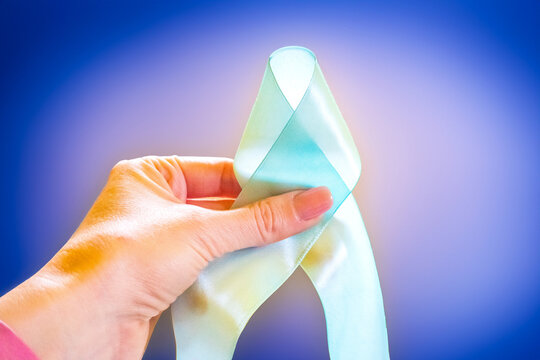 Woman hand holding Light blue, sky blue ribbons, Prostate Cancer Awareness