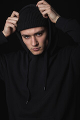Portrait of a young sad guy in black clothes on a black background. Depressive portrait.