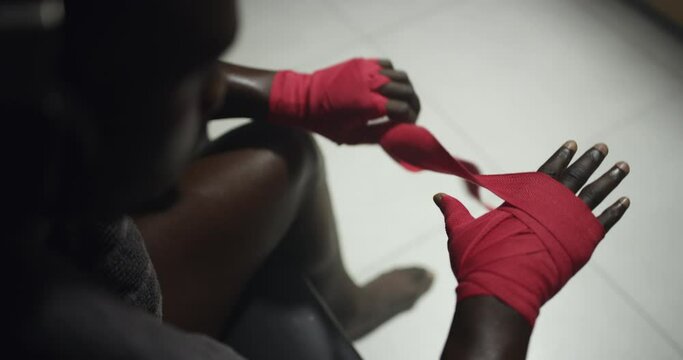 Person wrapping hands, kickboxing and sports for fitness in gym locker room and top view of athlete at MMA training. Boxer prepare for fight, challenge or competition with martial arts and exercise