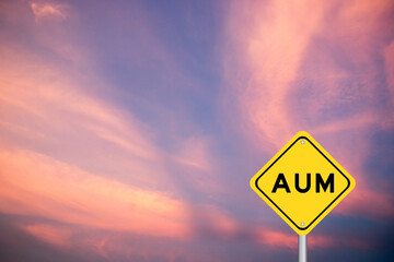 Yellow transportation sign with word AUM (Asset under management) on violet color sky background