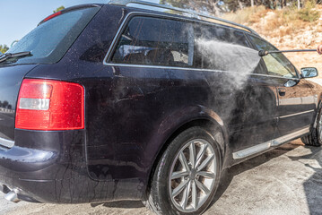 Car washing under the open sky. High-pressure washing car outdoors.