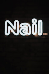 Fototapeta na wymiar Nails. Neon electricity fluorescent sign “Nail” concept illuminated vintage manicure salon. Glow icon logo text light Nail on billboard or signboard. Closeup. Sign on a black background.