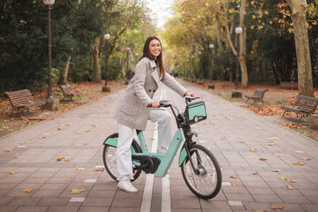 Obraz premium Portrait of smiling young latin woman riding an electric-bike in a park