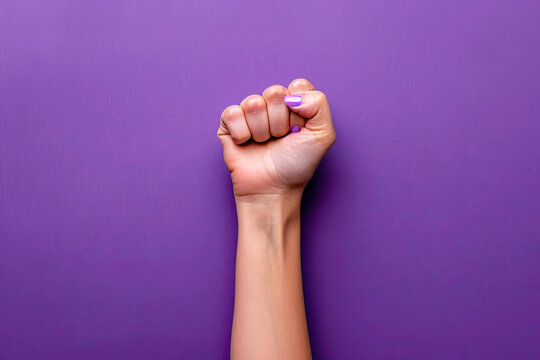 woman's hand with raised fist on purple background