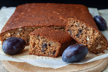 Traditional plum cake with nuts and cut into pieces on an wooden board close-up, selective focus.