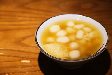 bowl of Glutinous rice balls in sweet rice wine on wooden table. Traditional Chinese dessert. Served during Lantern Festival and Dongzhi Festival in China