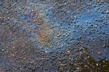 rainbow spots from spilled engine oil in puddle