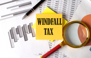 WINDFALL TAX text on a sticky on the graph background with pen and magnifier