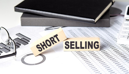 SHORT SELLING - text on a wooden block with chart and notebook