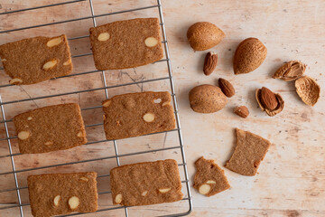 Thin crispy almond cookies or biscuits, a snack or dessert, on a cooling rack on a kitchen worktop....