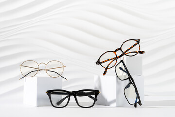 Trendy eyeglasses of different design on podiums on white background. Minimal still life. Copy...