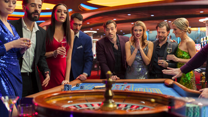 Successful Men and Women Partying in a Luxurious Casino. Young People Gambling at a Roulette Table,...