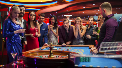 Casino Players Making Bets at a Roulette Table. Vibrant Crowd of International Young People...