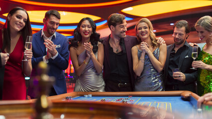 Casino Enthusiasts Making Calculated Bets at a Roulette Table. International Crowd of Young...