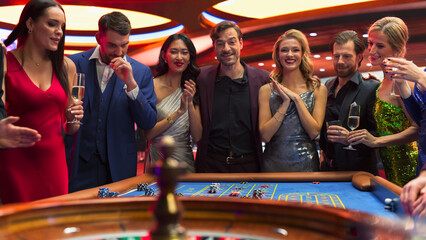Successful Men and Women Partying in a Luxurious Casino. Young People Gambling at a Roulette Table,...