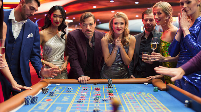 Elegantly Dressed Men and Women Enjoying Luxurious Atmosphere of a Casino. Cinematic Footage with Young People Placing Bets at the Roulette Table, Living a Lifestyle of Glamour and Entertainment