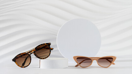 Classic tortoiseshell frame and trendy cat eye frame sunglasses on podiums on white background....