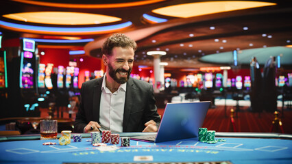 Portrait of a Young Man on Casino Floor, Using Laptop Computer to Play Online Casino Betting...