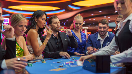 Happy Glamorous Couple Spending a Night Out in Stylish Modern Casino. Group of Diverse People Playing Blackjack and Gambling and Placing Bets. Private Social Club for Pleasant Leisure Time - obrazy, fototapety, plakaty