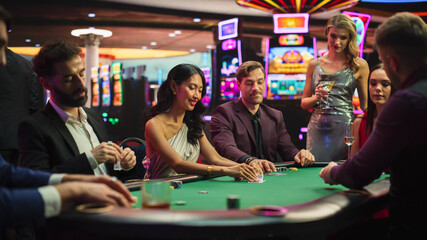 Group of Diverse Poker Players Sitting at a Table as the Croupier Deals the Playing Cards in a...