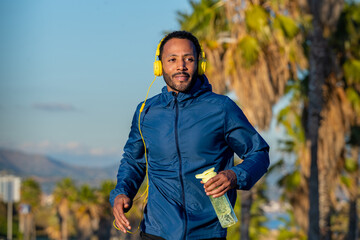  A young sportsman running through the streets of the city, holding a bottle of water.