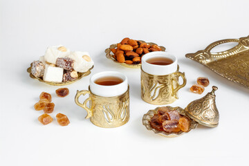 Hot tea in cups in Arabic or Turkish style with sweets and nuts