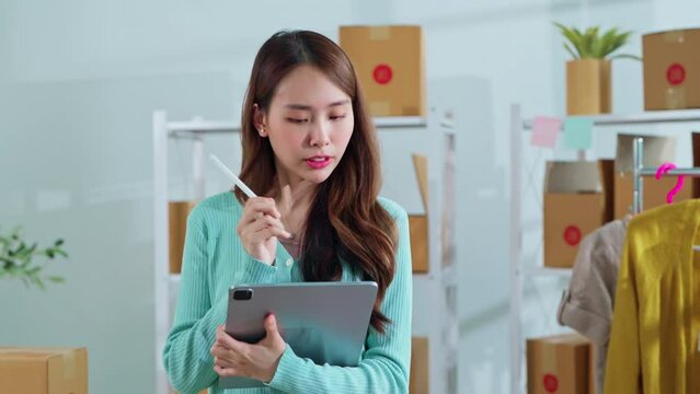 small business fashion store shop onwer discuss checking business order contract deal at home while conversation on ;aptop and tablet and checking cloth inventory and order checking for make sure 