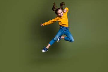 Fototapeta na wymiar Full size photo of cute small kid with tails hair wear pullover flying clenching fists near empty space isolated on khaki color background