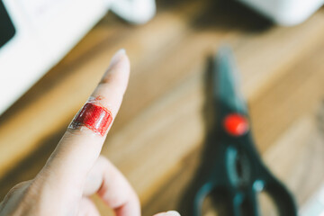 The hand of a person with a wound on the index finger and the bleeding does not stop even though it is covered with a plaster, concept of health insurance and accidents - obrazy, fototapety, plakaty