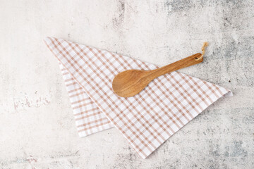 Kitchen background with wooden spoon on cotton towel over retro stone table.