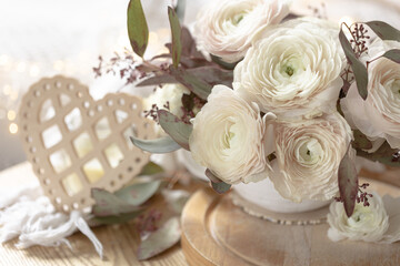 Bouquet of white ranunculus flowers on a blurred background with a heart.