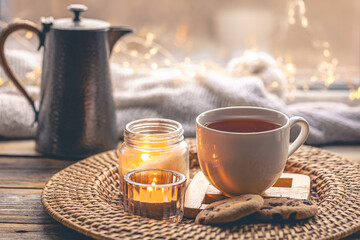 Cozy home composition with a cup of tea, candles and a teapot.