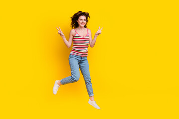 Fototapeta na wymiar Full size photo of optimistic lovely woman dressed knit top jeans jumping showing v-sign isolated on vivid yellow color background