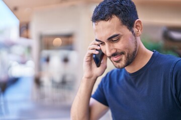 Young hispanic man smiling confident talking on the smartphone at street