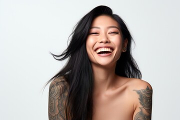 professional portrait studio photo of a handsome young asian american tatooed woman model with perfect clean teeth laughing and smiling. isolated on white background. for ads and web design
