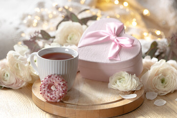 Romantic composition with a cup of tea, gift box and flowers.