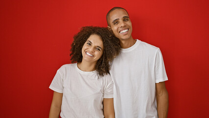 Two lovely people in love, a beautiful, confident couple standing together, smiling over an isolated red background, embodying happiness, joy and casual lifestyle.