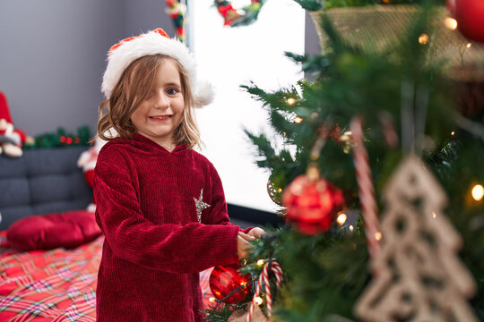 Adorable hispanic girl smiling confident decorating christmas tree at home