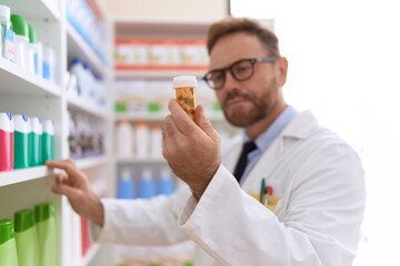 Middle age man pharmacist reading pills bottle label at pharmacy