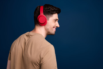 Side profile photo of positive man dressed beige t-shirt in headphones look at promo empty space...