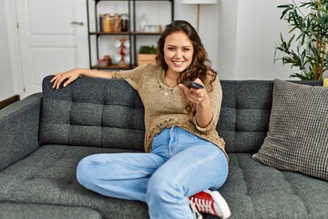 Obraz premium Young beautiful hispanic woman watching movie sitting on sofa at home